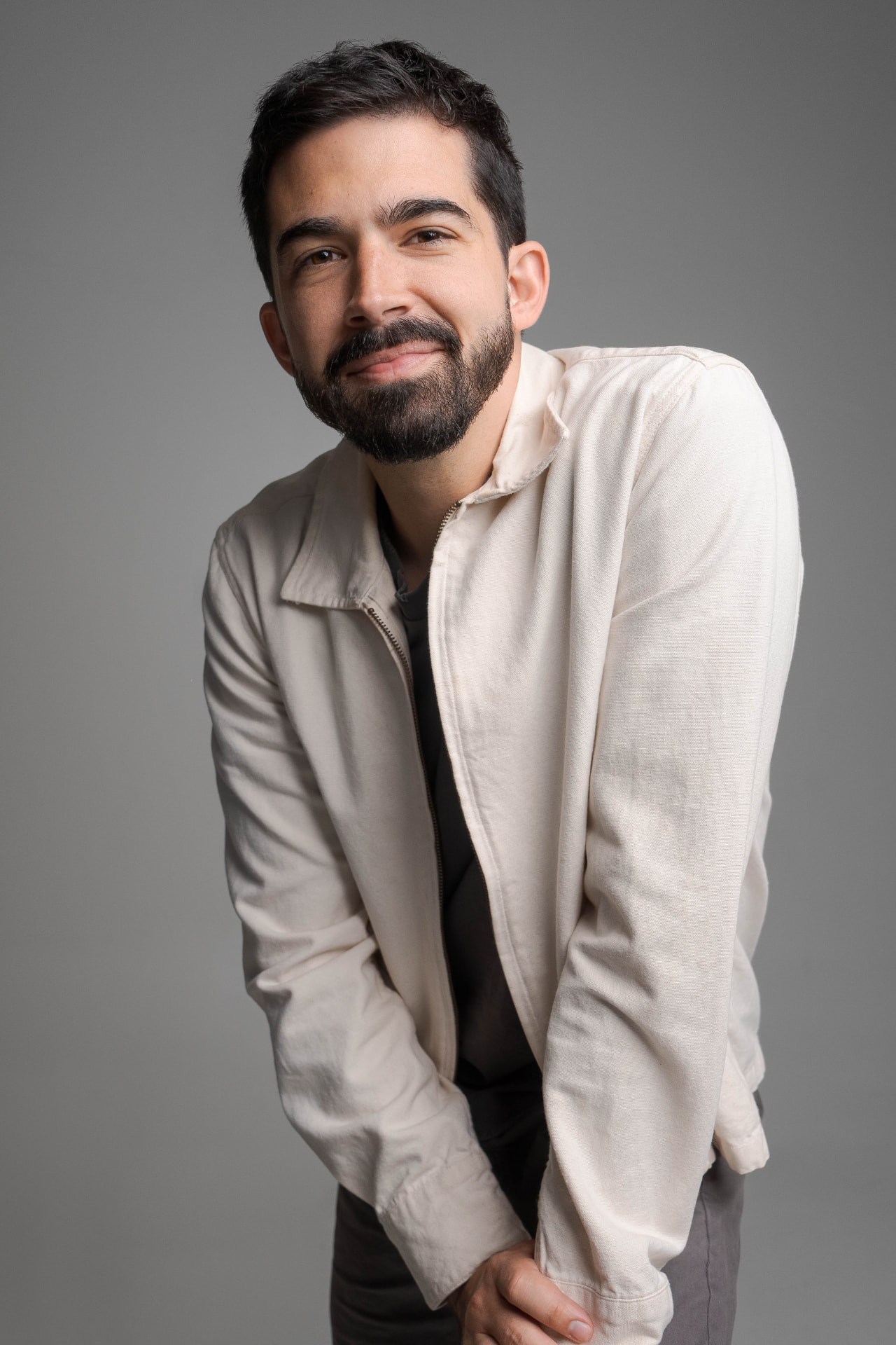 Alec Funiciello in a cream jacket, leaning toward camera